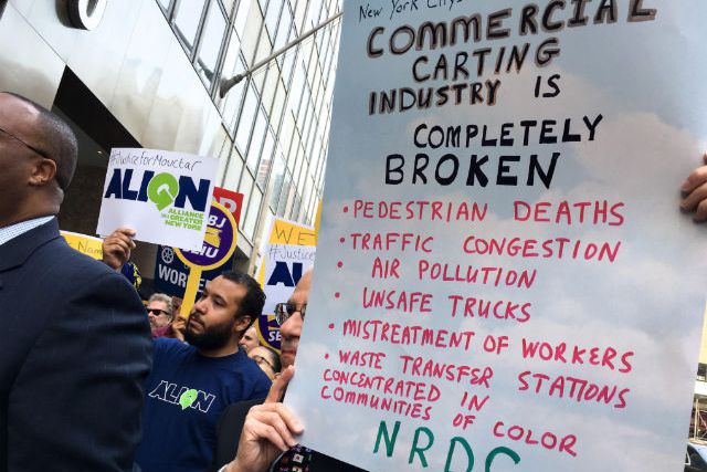 Protesters hold signs at the rally outside the Business Integrity Commission on Wednesday